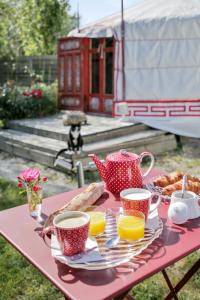 uma mesa de piquenique com uma bandeja de comida e chávenas de café em Yourte au Paradis em Souvigné