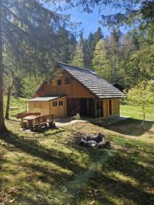 Cabaña de madera con mesa de picnic y bancos en un campo en Koča v gozdu en Bled