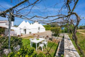 ogród ze stołem i krzesłami przed białym domem w obiekcie La Casa Sulla Roccia Trulli Pool - Happy Rentals w mieście Monopoli