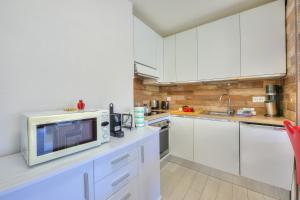 uma cozinha com armários brancos e um micro-ondas em Casa Bruna Few Min From Lake - Happy Rentals em Caslano