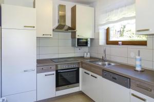 una cocina con armarios blancos y fregadero en House Kolpa Paradise Whirlpool and Sauna, en Metlika