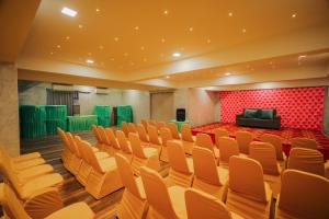 an empty auditorium with orange chairs and a red wall at HOTEL EVERLAND in Rajkot