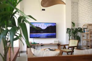 韋利格默的住宿－OASIA - Boutique Surf House (ADULTS ONLY)，客厅配有书桌和墙上的电视