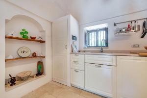 cocina con armarios blancos, fregadero y ventana en Trullo Fedele Grande125 - Happy Rentals, en Ceglie Messapica