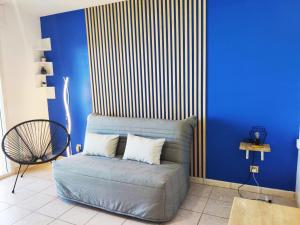- un canapé dans une chambre dotée d'un mur bleu dans l'établissement Joli appartement aux Minimes avec Parking, à La Rochelle