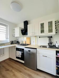 a kitchen with white cabinets and a stainless steel dishwasher at ApartOne in Gorlice