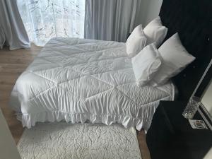 Una cama blanca con almohadas blancas encima. en Urban Fourways Haven, en Sandton