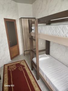 a room with two bunk beds with a door and a rug at Hostel Highway in Samarkand