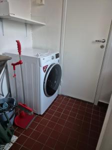 eine Waschmaschine in einer Küche mit roten Fliesenböden in der Unterkunft Jakan in Stockholm