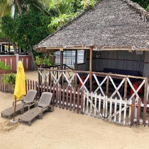 two chairs and an umbrella in front of a hut at Villa Madirokely in Nosy Be