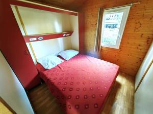 a small red bed in a room with a window at Chalet Agde, 3 pièces, 6 personnes - FR-1-607-59 in Agde