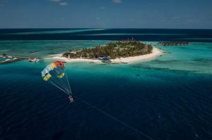 a person riding a parachute over an island in the ocean at Fushifaru Maldives - 50 percent discount on transfers till 30 Sep 2024 on FB & AI for 04 nights or above in Fushifaru