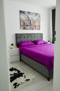 a bedroom with a purple bed and a painting on the wall at Artec Magnolia Apartment in Sibiu