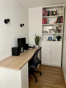 ein Büro mit einem Schreibtisch mit einem Computer und einem Bücherregal in der Unterkunft Uus korter väga heas asukohas in Pärnu