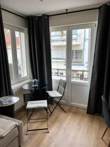uma sala de estar com duas cadeiras e uma mesa e duas janelas em La Dunette, appt cozy à 150 m de la plage em Merlimont