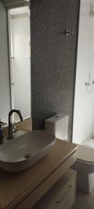 ein Badezimmer mit einem Waschbecken, einem WC und einem Spiegel in der Unterkunft Quarto Central Ótimo Custo Benefício in Dourados