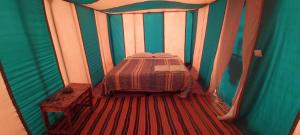 um quarto com uma cama num quarto listrado em Chigaga Desert Camp em M'hamid