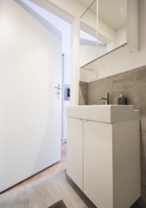 uma cozinha branca com um lavatório e um espelho em Apartament przy Woonerfie em Lódź