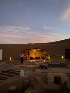 zwei Menschen stehen vor einem Gebäude in der Wüste in der Unterkunft Chigaga Desert Camp in M’hamid El Ghizlane