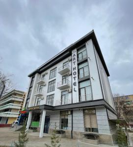 un gran edificio blanco con un cartel. en Art Hotel Navoiy, en Navoi