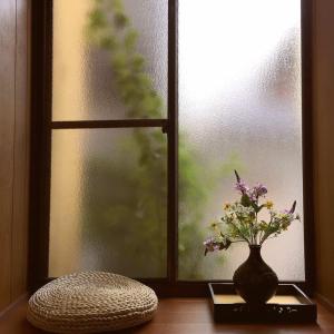 a vase with flowers sitting on a table next to a window at 百合の家 in Kyoto