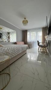 a bedroom with a bed and a table and a chair at Gold Glamour Apartment Sopot z dwoma sypialniami, duzy balkon in Sopot