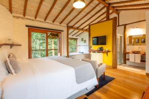 a bedroom with a white bed and a kitchen at Pousada Casa Campestre in Gonçalves +48 photos