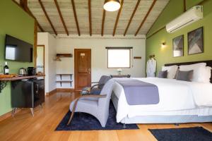 a bedroom with a large white bed and green walls at Pousada Casa Campestre in Gonçalves
