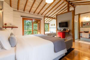 a bedroom with a large white bed and a television at Pousada Casa Campestre in Gonçalves