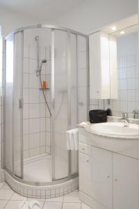 a white bathroom with a shower and a sink at Hotel Parkfrieden in Timmendorfer Strand