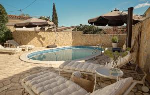 a swimming pool with two lounge chairs and an umbrella at Stunning Home In Vrboska With Kitchen in Vrboska