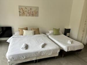 2 Betten in einem Zimmer mit weißer Bettwäsche und Hausschuhen in der Unterkunft Lumineux Appart à Disneyland in Montry