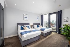 Luxury & Spacious 2 BR APT with City Views في لندن: سريرين في غرفة مع نافذة