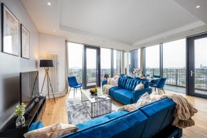 a living room with a blue couch and large windows at Luxury & Spacious 2 BR APT with City Views in London