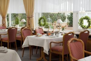 a dining room with tables and chairs and windows at Hotel Parkfrieden in Timmendorfer Strand