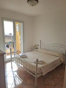 un letto bianco in una camera con balcone di ALICE B&B a Villasimius
