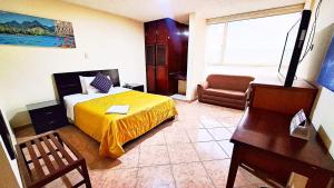a bedroom with a bed and a desk and a chair at Hotel Xilon Resort Plaza in Pasto