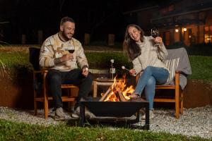 Un homme et une femme assis autour d'un feu dans l'établissement Pousada Casa Campestre, à Gonçalves