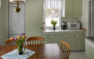a kitchen with a table with a vase of flowers on it at Gorgeous Home In Vimmerby With Kitchen in Vimmerby