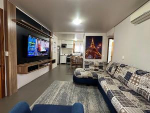 sala de estar con sofá y TV de pantalla plana en Apartamento Coração de Gramado, en Gramado