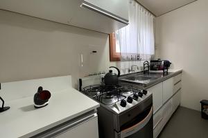 une cuisine avec une cuisinière et un évier dans l'établissement Apartamento Coração de Gramado, à Gramado