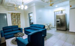ein Wohnzimmer mit blauen Stühlen und einem Kühlschrank in der Unterkunft Crislord Palace Hotel in Takoradi