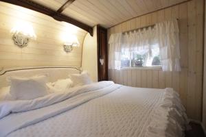 1 dormitorio con 1 cama blanca grande y ventana en Walentynka - romantyczny domek 2-os z prywatnym ogródkiem en Stegna