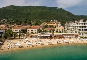 a beach with chairs and umbrellas in the water at Villa Sea-N-Sun, 7 bedrooms & Pool, nearby Portonovi Marina. in Ðenovići