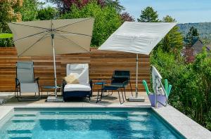 a patio with chairs and an umbrella and a pool at Panoramahaus am Schlipfweg in Weil am Rhein