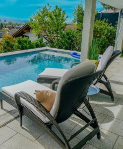 a couple of chairs sitting next to a swimming pool at Panoramahaus am Schlipfweg in Weil am Rhein