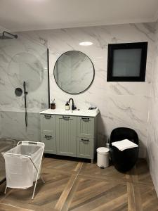 a bathroom with a sink and a mirror and a chair at מבית תכלת פתרונות נופש Allentown 21 אלנטאון 21 in Tiberias