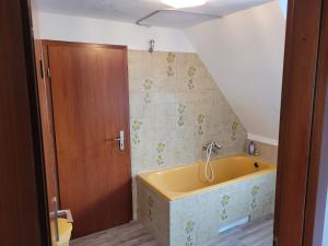La salle de bains mansardée est pourvue d'une baignoire jaune. dans l'établissement City- und Messeapartment Hildesheim, à Hildesheim