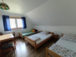 a room with three beds and a table and a window at Maślana Chata in Sokolec