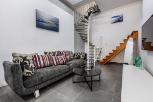 a living room with a couch and a staircase at Private duplex home in the heart of St Julians in St Julian's